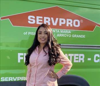 Female smiling with light orange shirt, SERVPRO van in background 